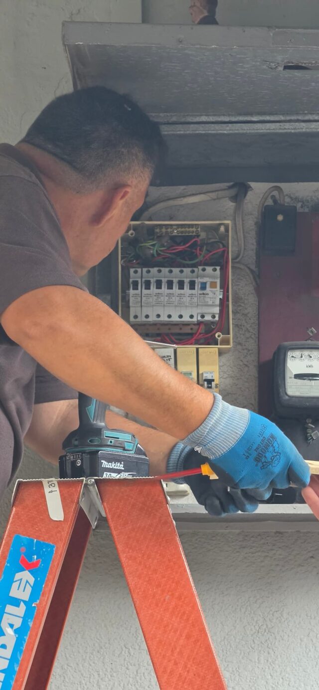 Electrician upgrading an older switchboard with RCBO safety switches during a defect rectification in Rosebery